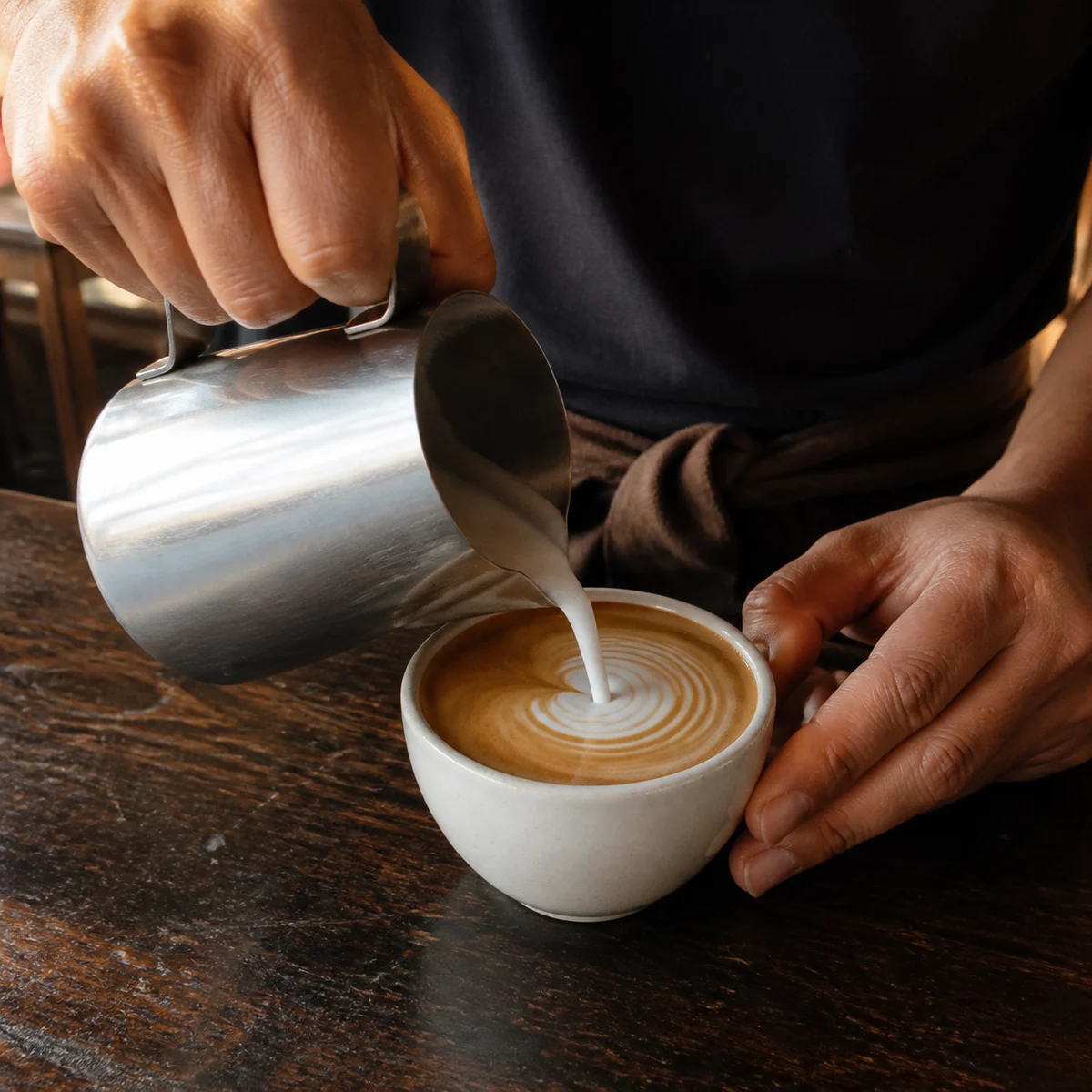 AI-generated concept photograph of barista hands pouring milk into coffee